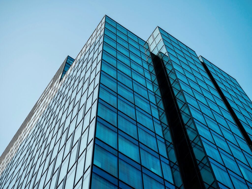 Low angle view of a modern skyscraper with a reflective glass facade reaching into a clear blue sky.
